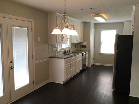 A kitchen with white cabinets and black countertops.