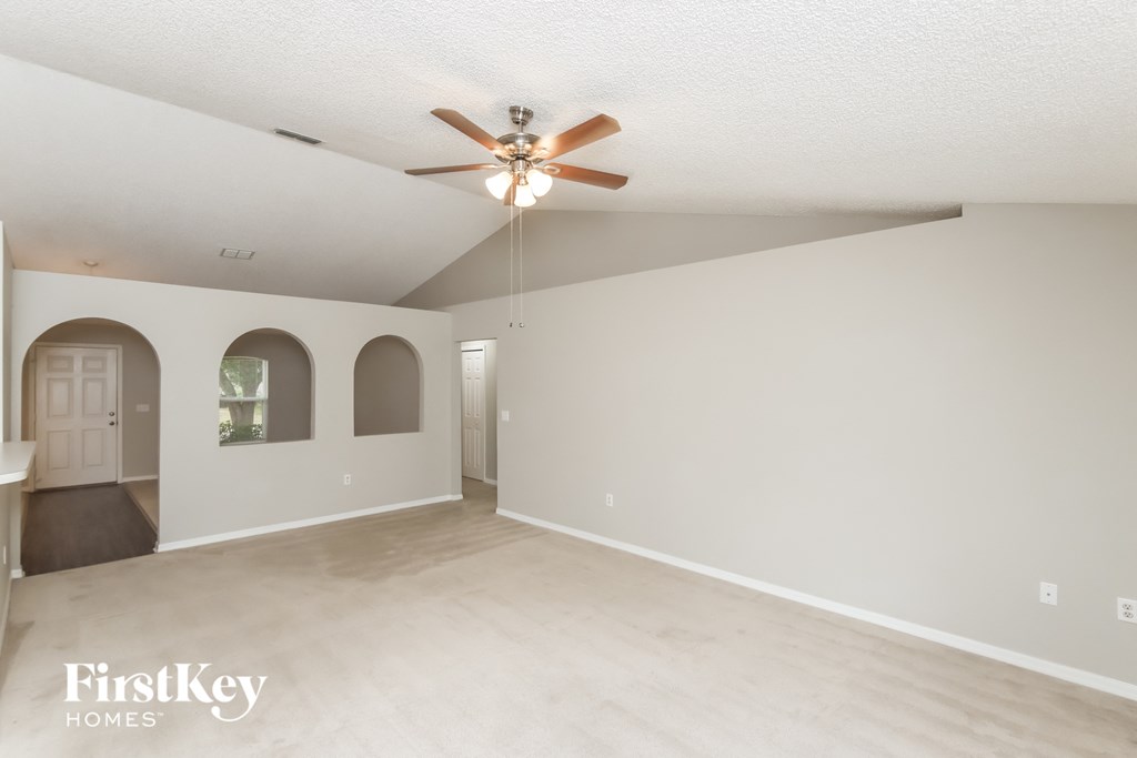 A spacious room with a ceiling fan and arched windows.