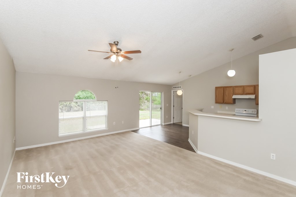 A spacious living room with a ceiling fan and sliding glass doors.