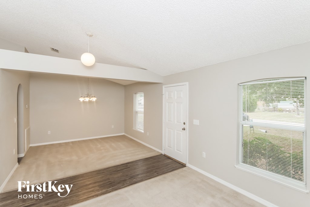 A spacious room with a wooden floor and a large window.