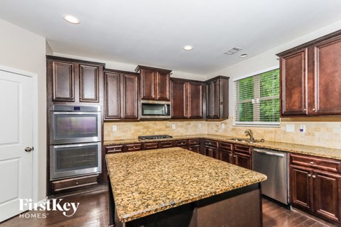 a kitchen with granite countertops and wooden cabinets and stainless steel appliances