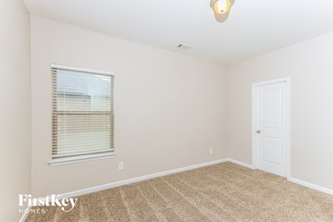 a bedroom with carpet and a window and a white door
