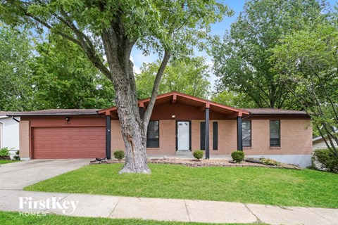 a small brick house with a tree in the front