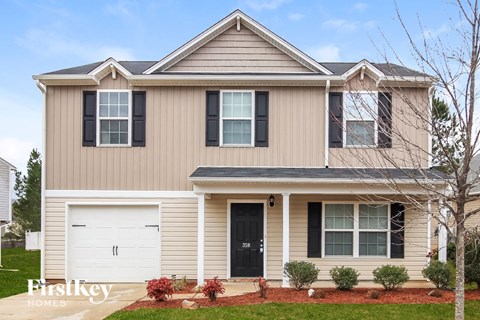 a tan house with black shutters and a white garage door