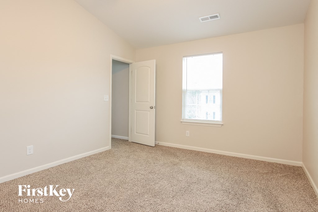 a bedroom with a door and a window and a carpeted floor