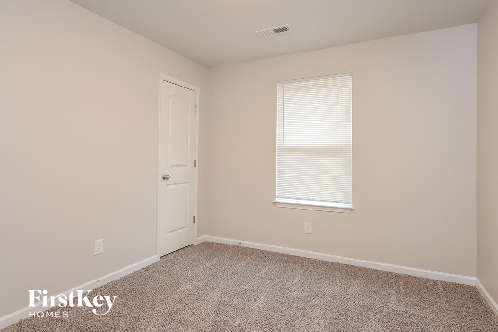 a bedroom with carpet and a door and a window