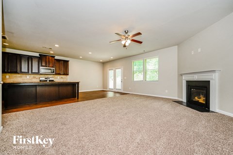 A spacious living room with a fireplace and a ceiling fan.