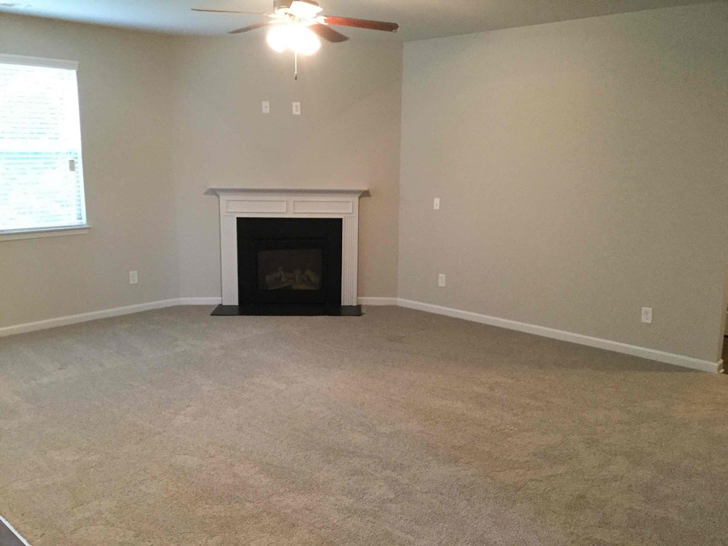 A living room with a fireplace and a ceiling fan.