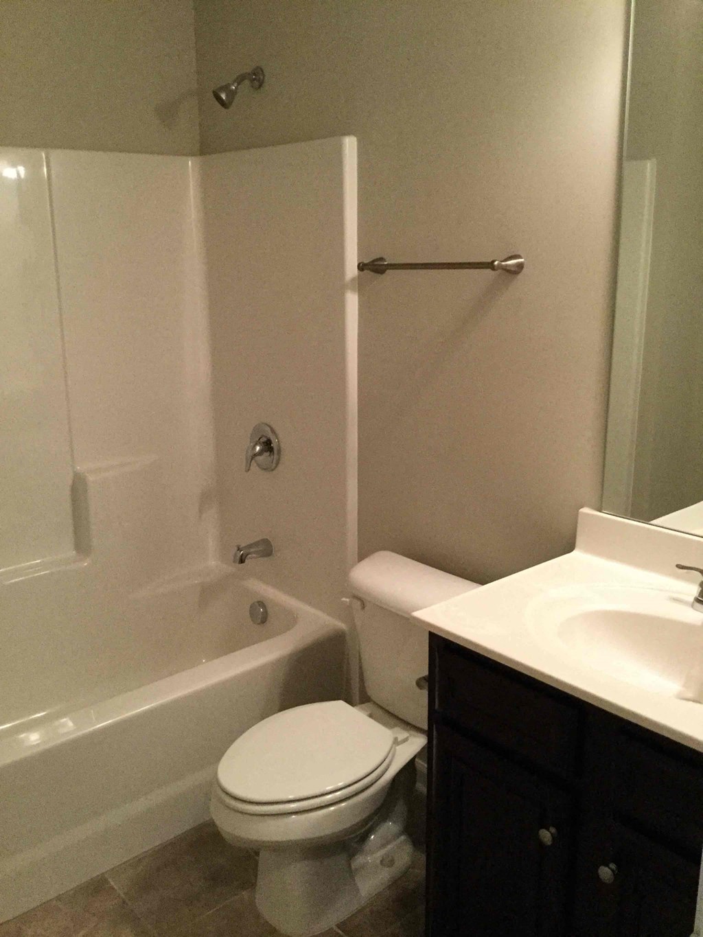 A white toilet sits in a bathroom next to a bathtub and sink.