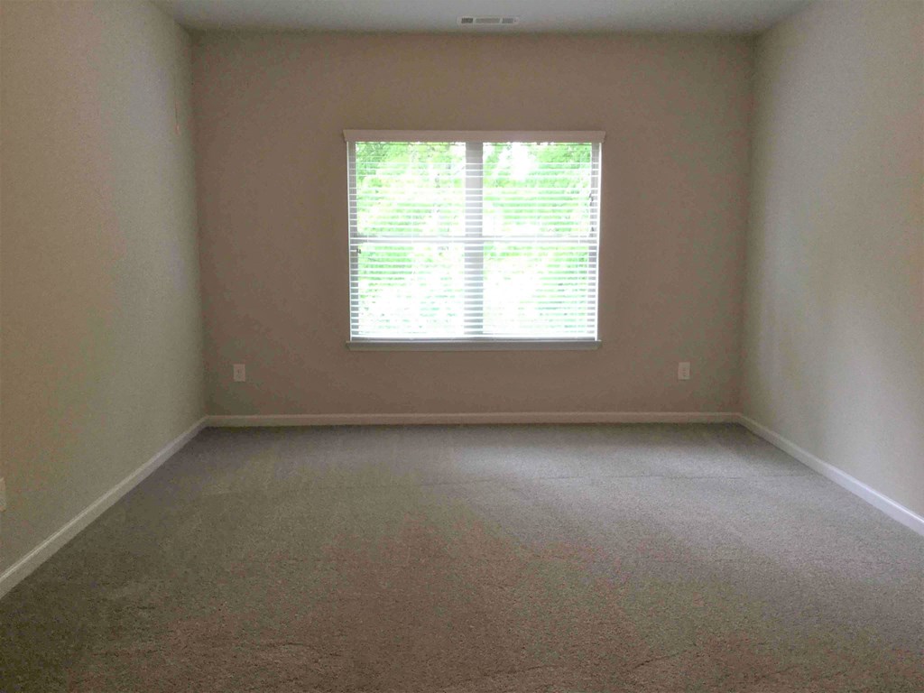 A room with a window covered by white blinds.