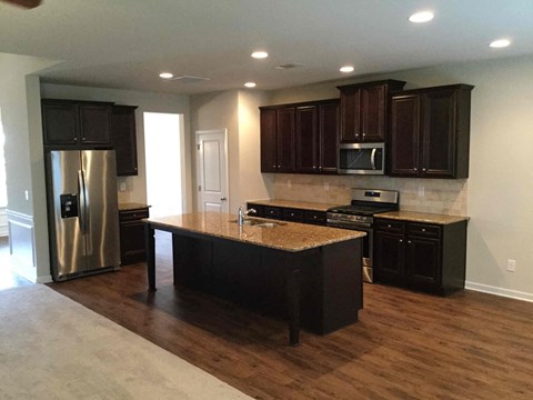 A kitchen with dark wood cabinets and a granite countertop.