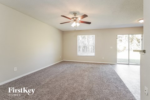 an empty living room with a ceiling fan and a window