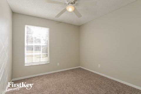 an empty room with a ceiling fan and a window