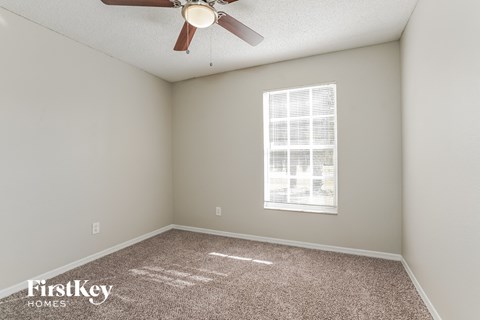 an empty room with a ceiling fan and a window