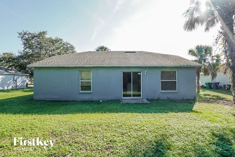 a small white house with grass and a palm tree
