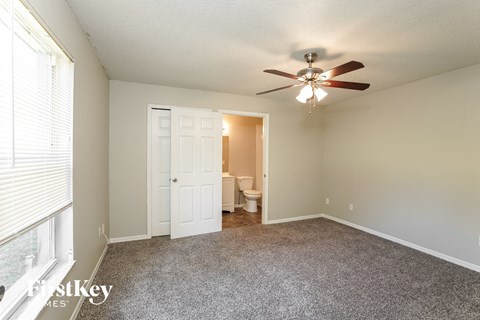 an empty living room with a ceiling fan and a door to the bathroom
