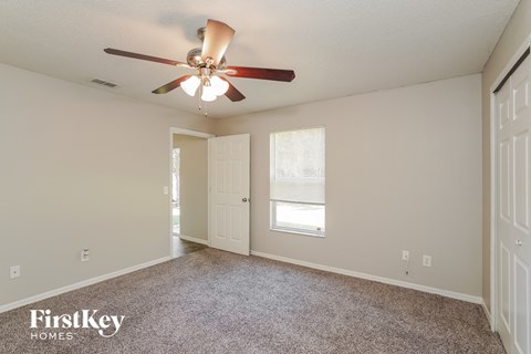 the spacious living room with ceiling fan and carpeting
