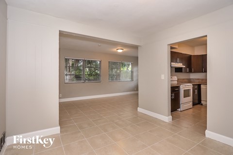 A spacious room with a kitchen area visible through the doorway.