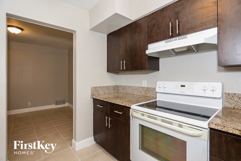 A kitchen with a stove top oven and wooden cabinets.