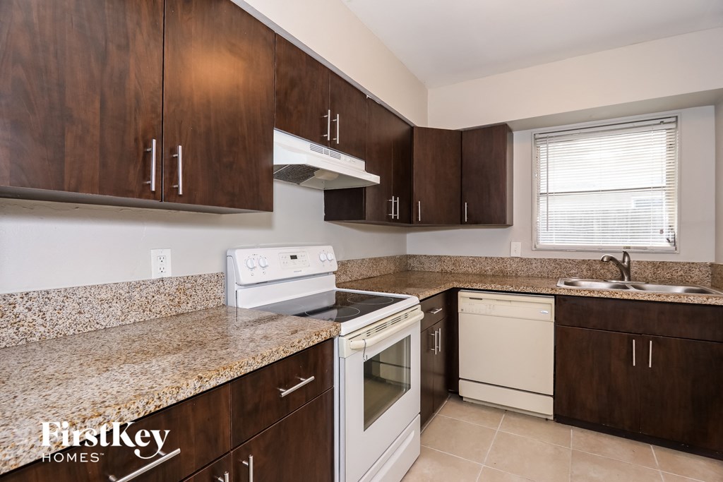 A kitchen with brown cabinets and a granite countertop.