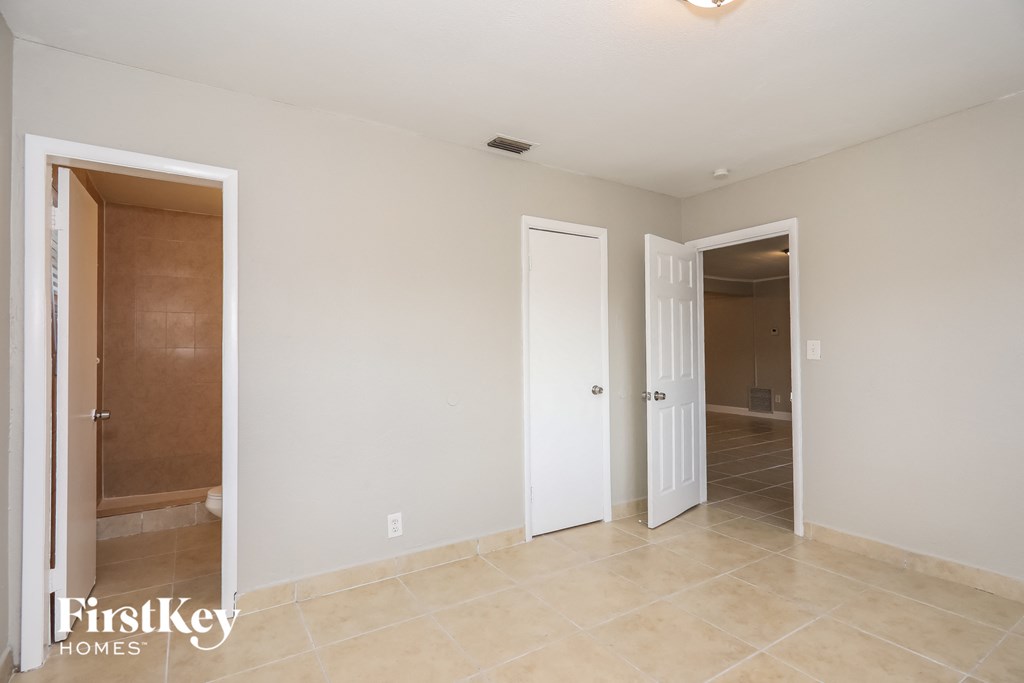 A room with two doors, one of which is open, and a tiled floor.