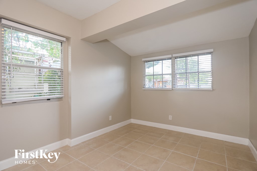 A room with two windows and a tiled floor.