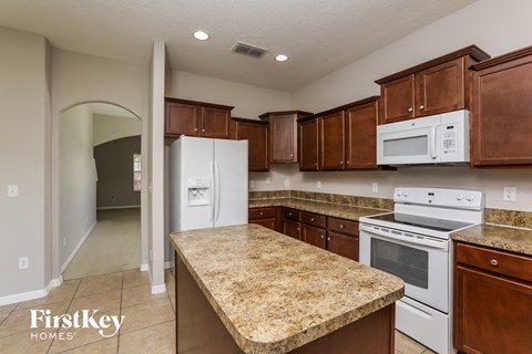 A kitchen with a granite countertop and white appliances.
