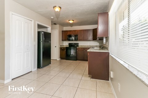 A kitchen with a black fridge and brown cabinets.