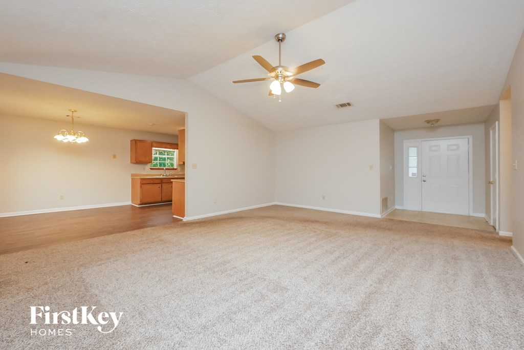 an empty living room and kitchen with a ceiling fan