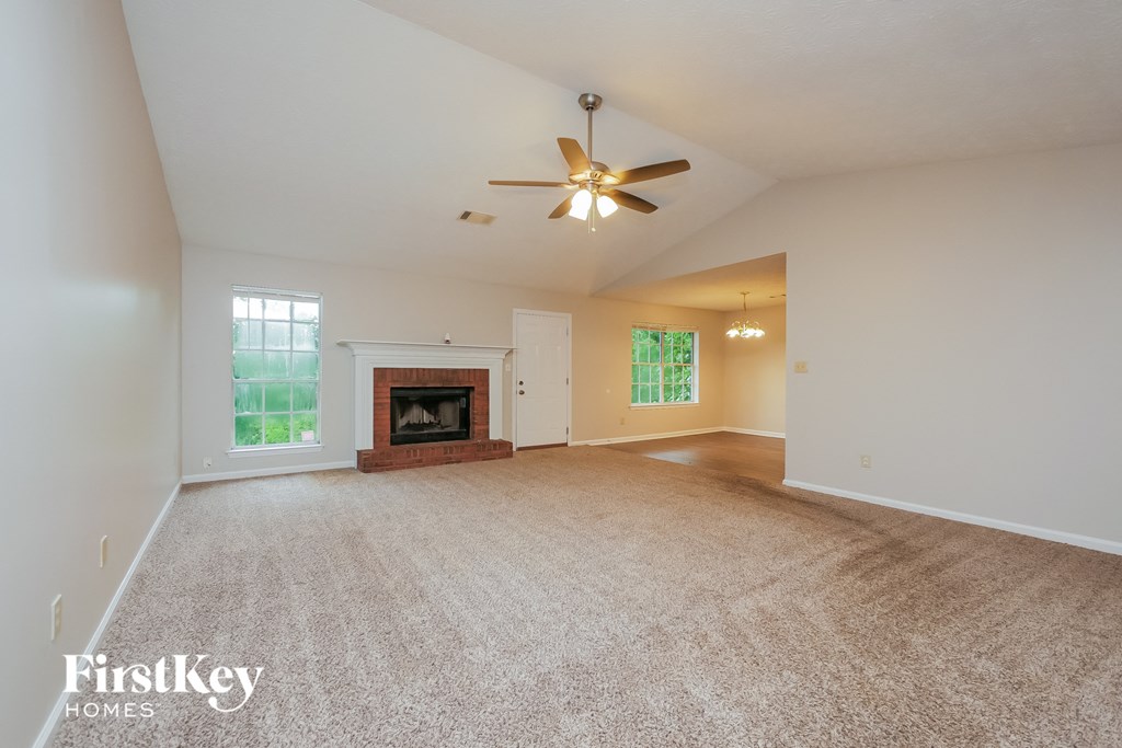 an empty living room with a fireplace and a ceiling fan