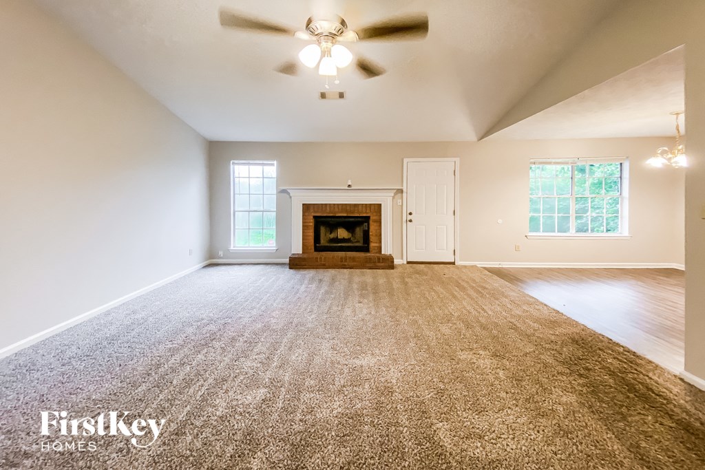 an empty living room with a fireplace and a ceiling fan