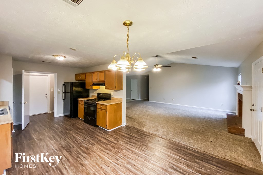 the living room and dining room of an empty house with wood floors and a kitchen