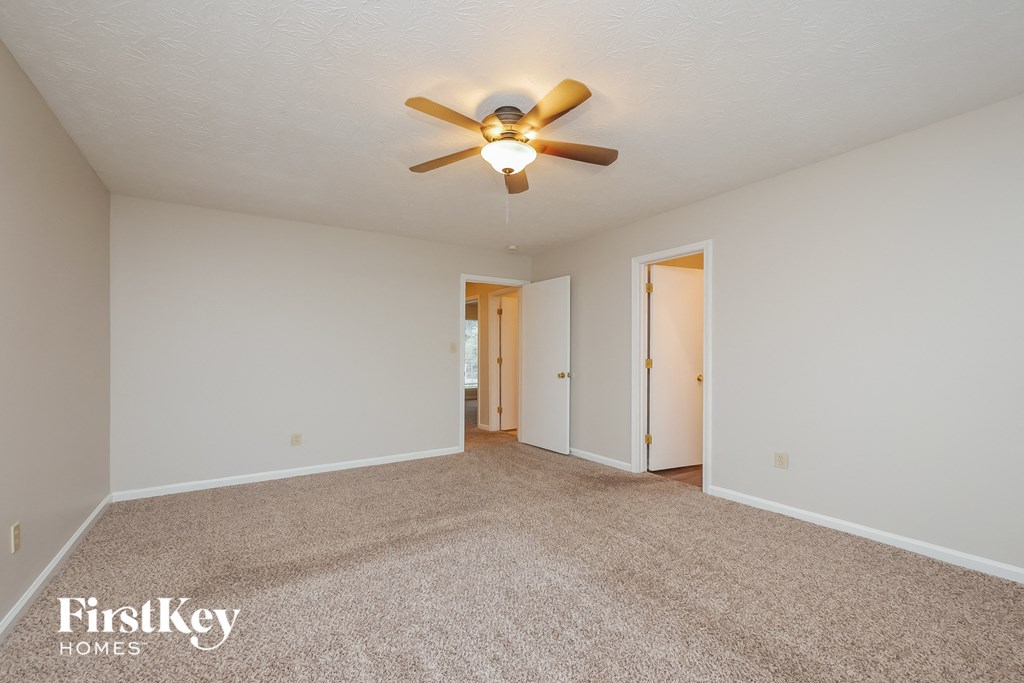 a spacious living room with carpet and a ceiling fan