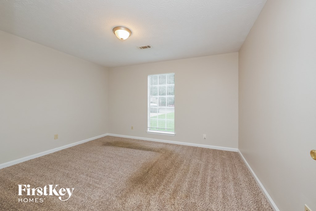 a spacious living room with carpet and a window