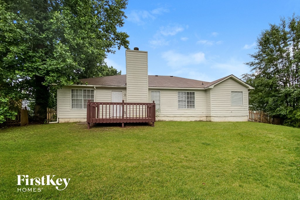 a backyard with a deck and a white house