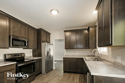 A kitchen with dark wood cabinets and a stainless steel refrigerator.