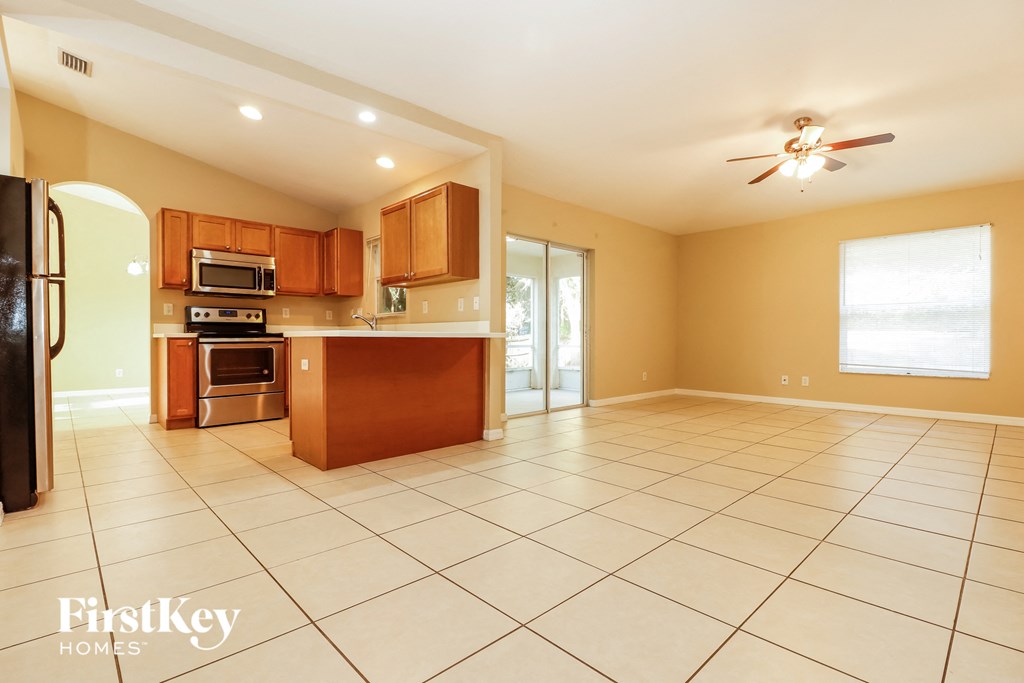 an open kitchen and living room with tile floors and wooden cabinets