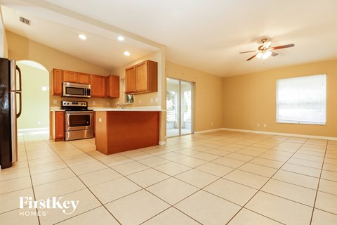 an open kitchen and living room with tile floors and wooden cabinets