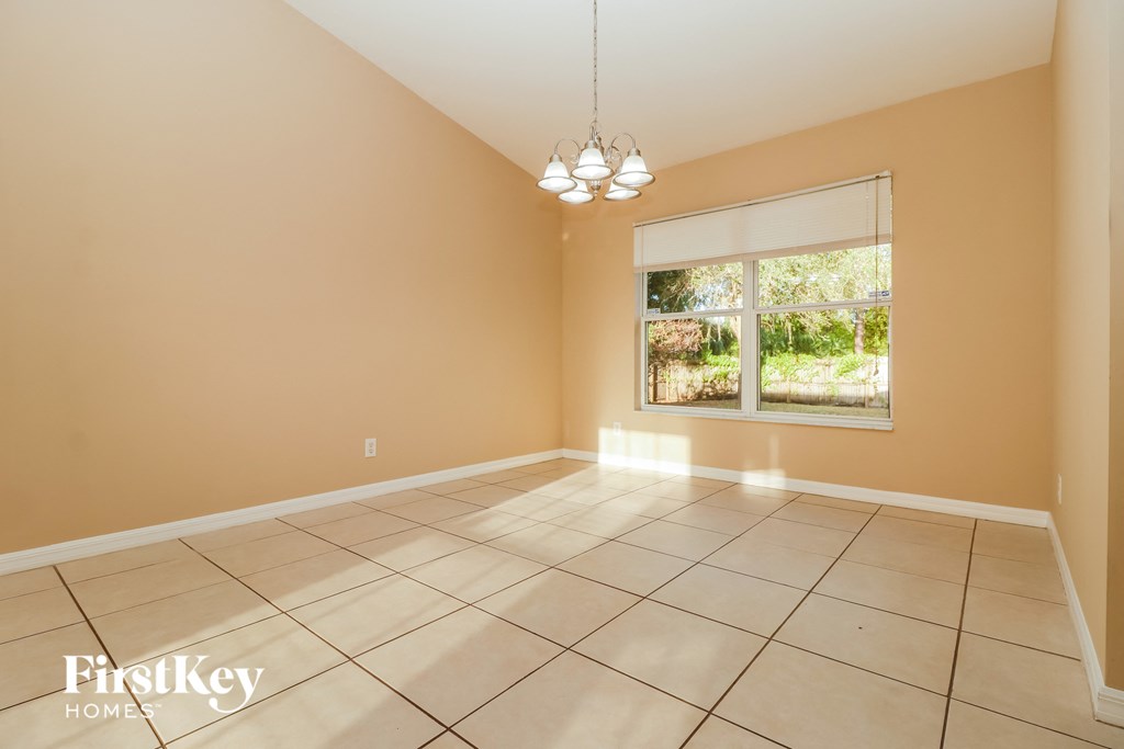 an empty living room with a large window and tiled floors