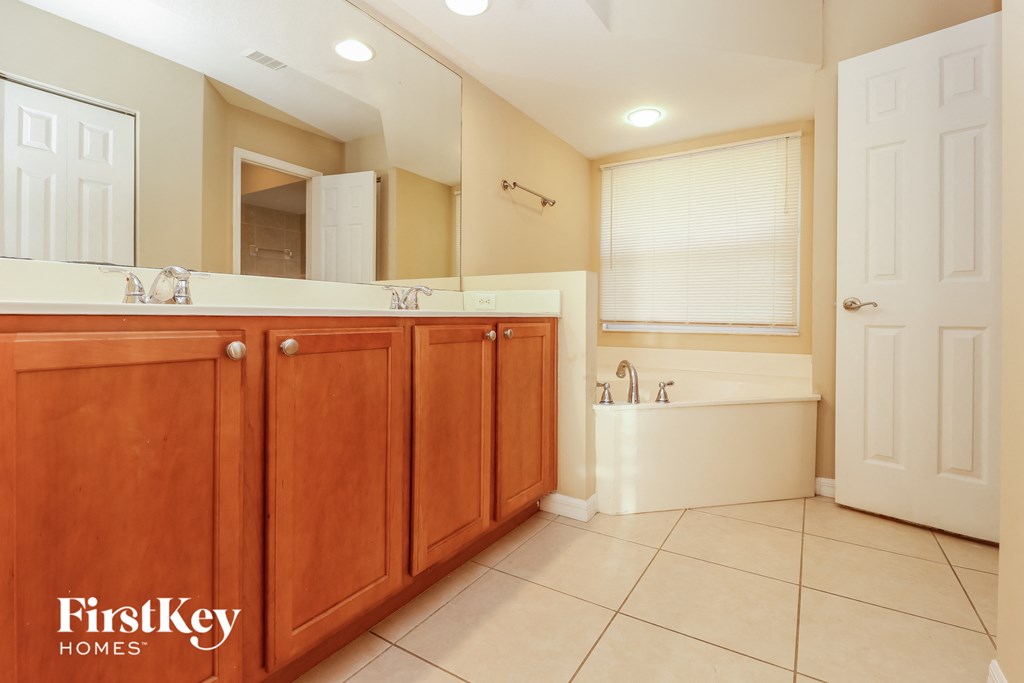 a bathroom with wooden cabinets and a tub and a sink
