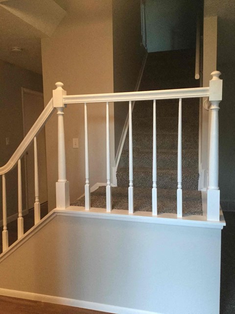 a white staircase with white railings and a carpeted floor