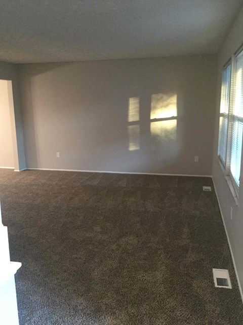 an empty living room with a carpeted floor