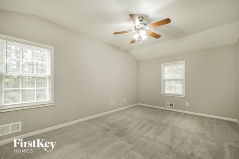 a spacious living room with carpet and a ceiling fan