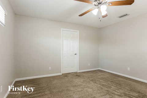the spacious living room with carpet and a ceiling fan