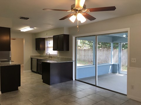 A kitchen with black cabinets and a ceiling fan.