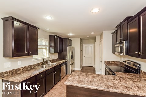 A kitchen with dark brown cabinets and granite countertops.