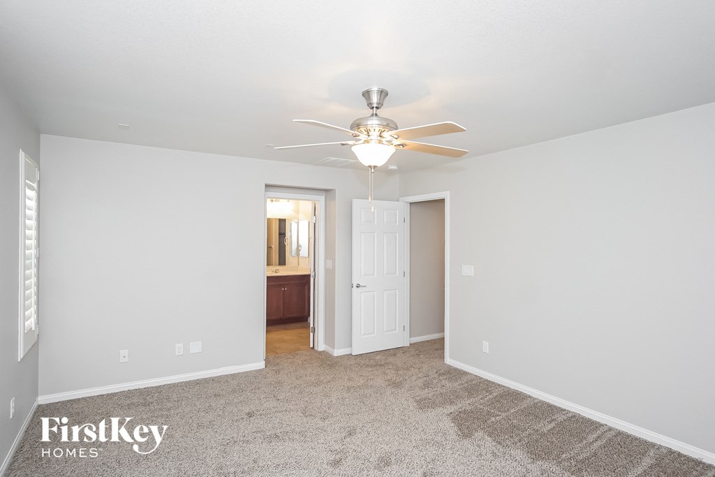 a bedroom with a ceiling fan and a door to a bathroom