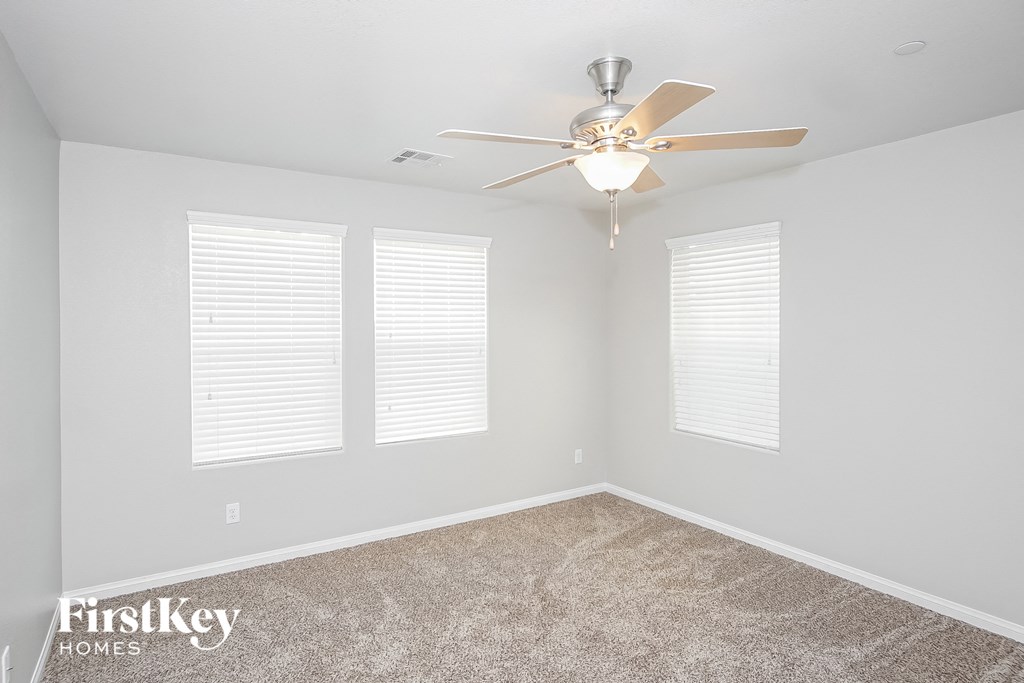a bedroom with a ceiling fan and three windows
