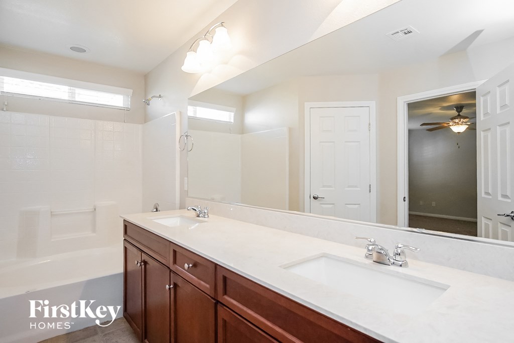 the master bathroom has a large mirror and two sinks