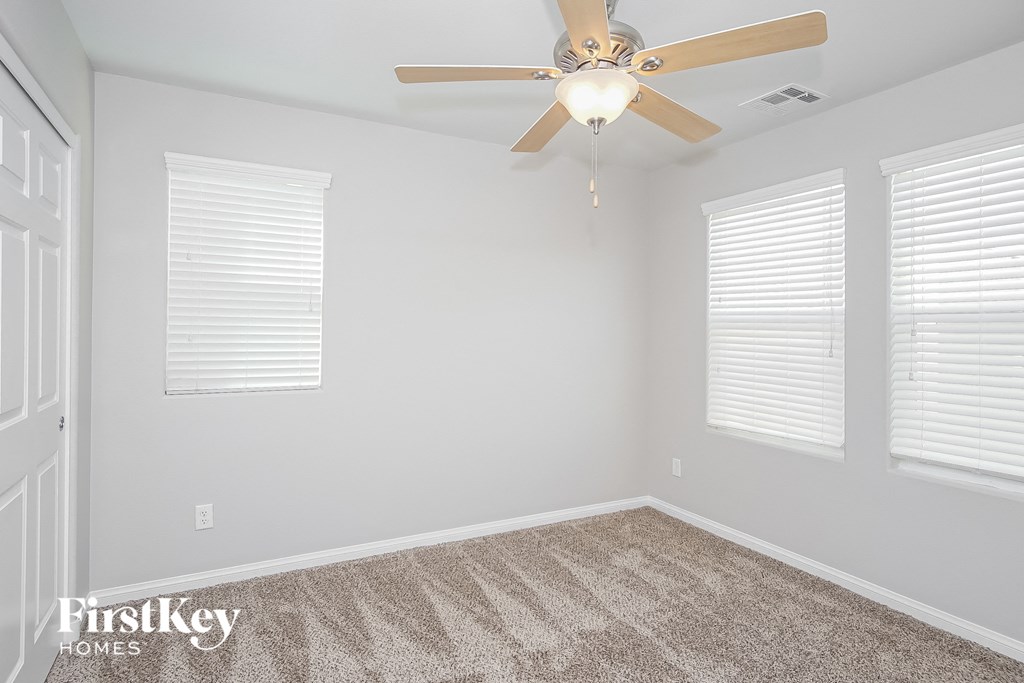 a bedroom with a ceiling fan and three windows